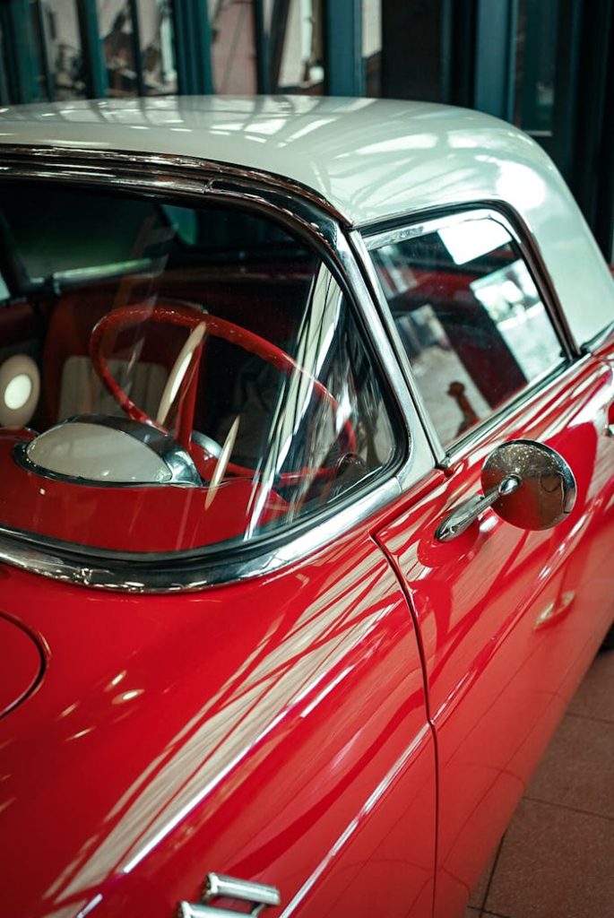 A vintage red convertible displayed in an indoor garage setting, showcasing its classic design.